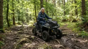 An off-road capable all-terrain power wheelchair for uneven ground tackling a bumpy dirt trail in the woods.